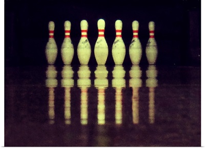Standing bowling pins with ground reflections.