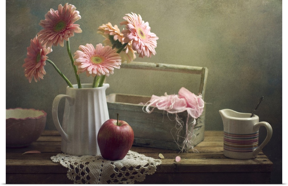 Still life with pink gerberas and red apple on table.