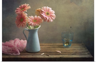 Still life with pink gerberas flowers in blue pitcher jug anf glass of water.