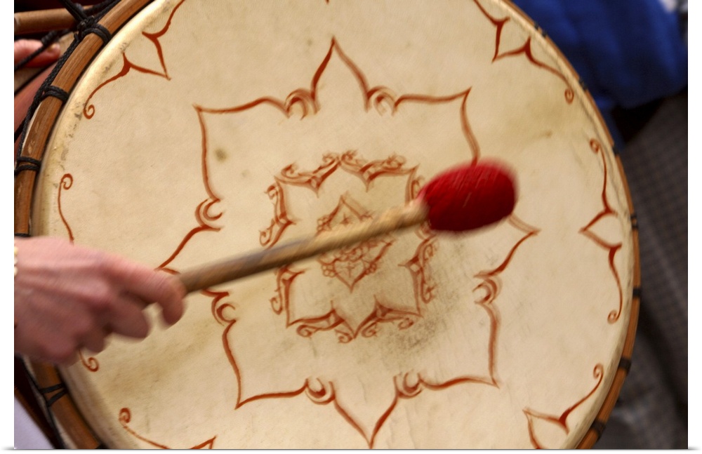 Striking Celtic bohdran drum with a drumstick