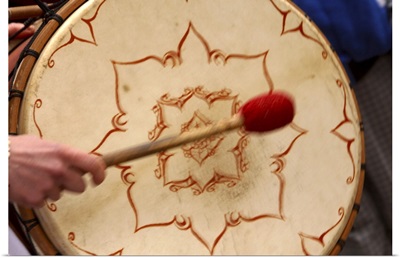 Striking Celtic bohdran drum with a drumstick