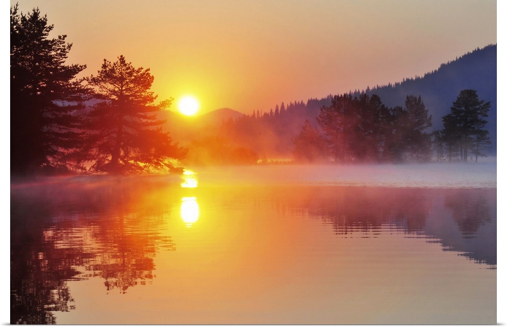 Sunrise at mountain lake with island of pine trees.