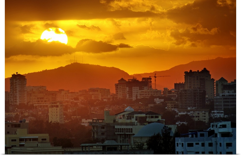 Sunset, Santo Domingo, Domenican Republic, large sun, cloudy sky, orange mood, mountains in background, romantic urban scape.