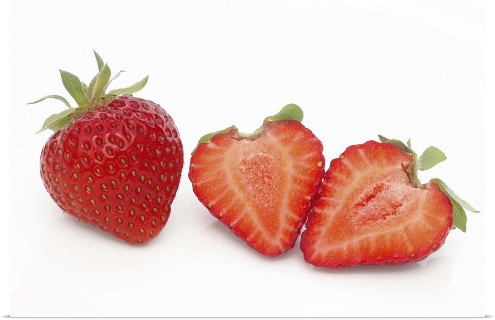 Two fresh, ripe, home grown, organic strawberries, one cut into two halves, on a white background.