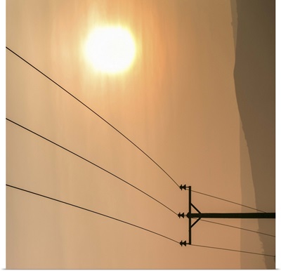 Telephone wires and pole with sunset in background.