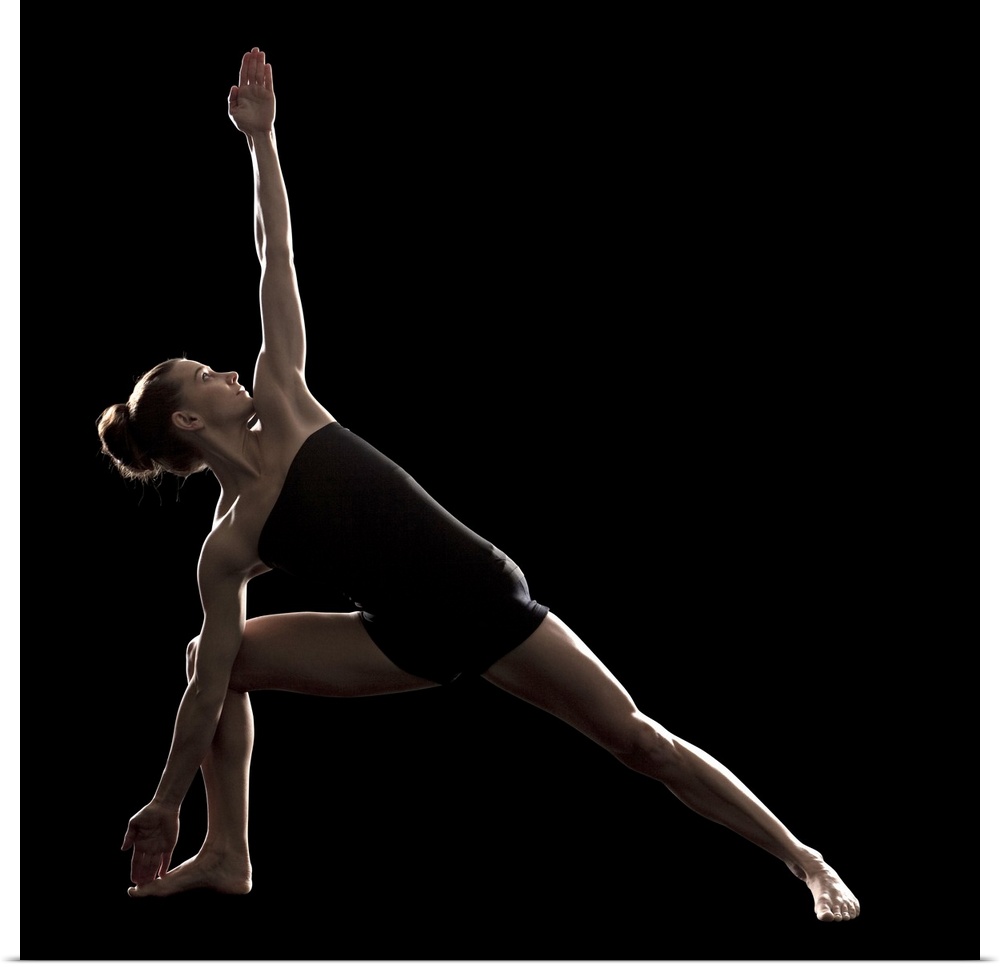 Studio shot of young woman practicing yoga.  The extended side angle pose, utthita parsvakonasana.