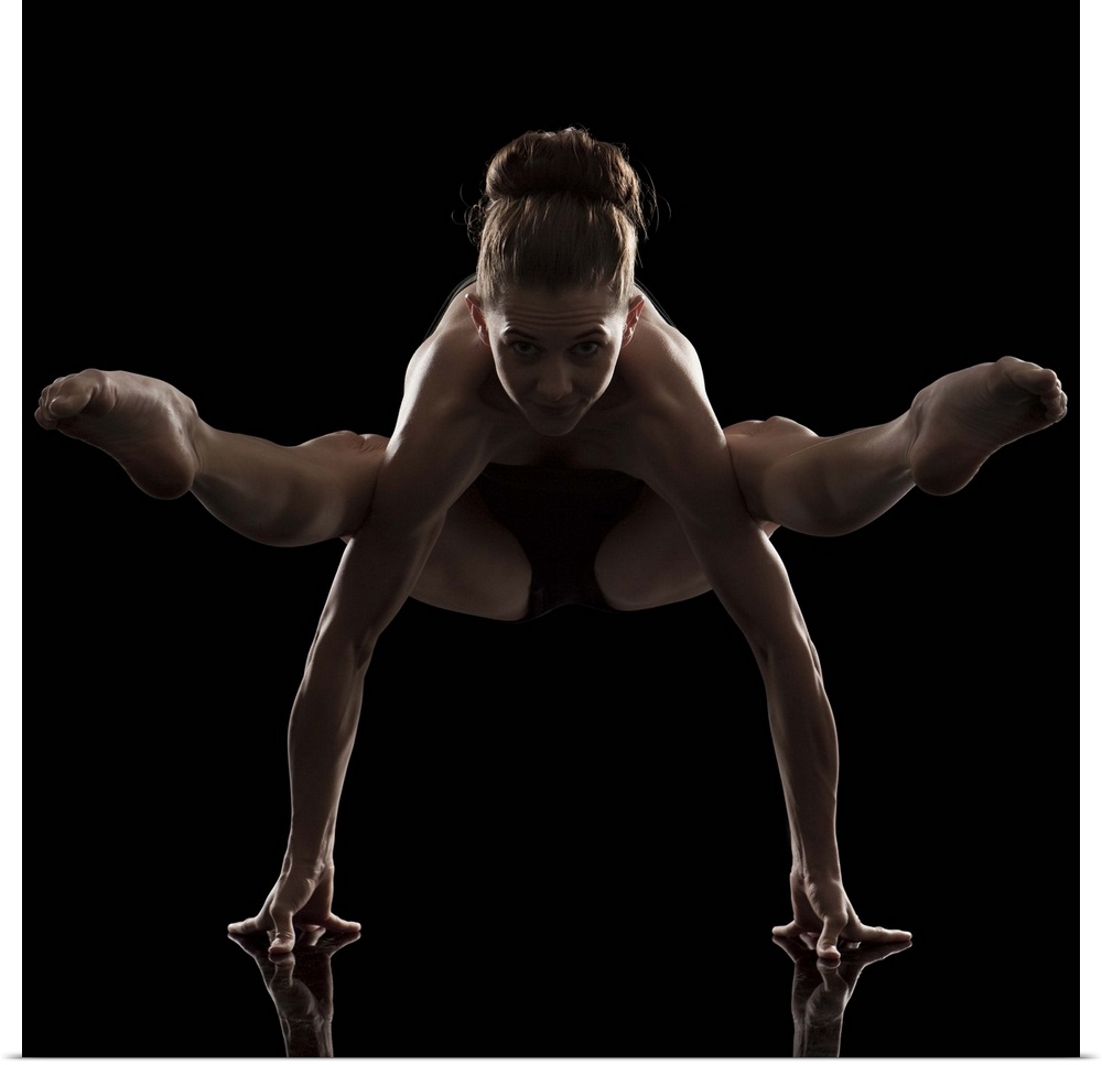 Studio shot of young woman practicing yoga.  The firefly pose, tittibhasana
