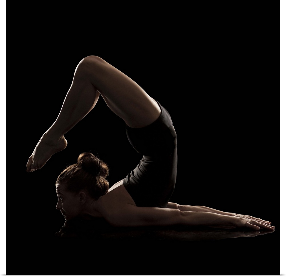 Studio shot of young woman practicing yoga.  The scorpion pose, vrshikasana