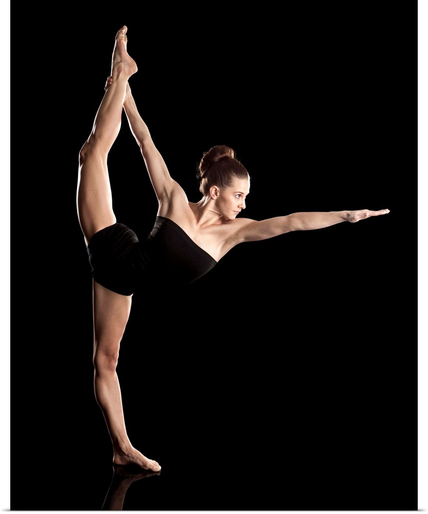 Studio shot of young woman practicing yoga.  The standing bow pose, Dandayamana Dhanurasana.