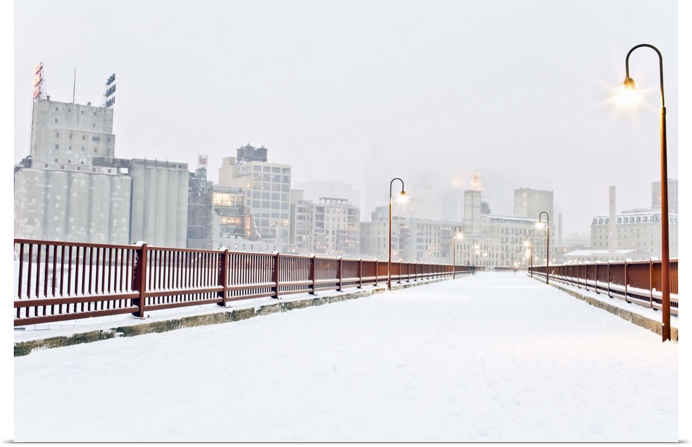 The Stone Arch Bridge in Minneapolis Minnesota during winter with snow on it.