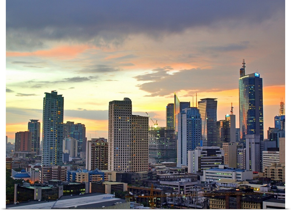 The sun setting light up low clouds over the Makati City, Manila Skyline. Many Tall buildings and a crane are seen with th...