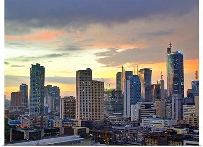 The sun setting light up low clouds over the Makati City, Manila Skyline.