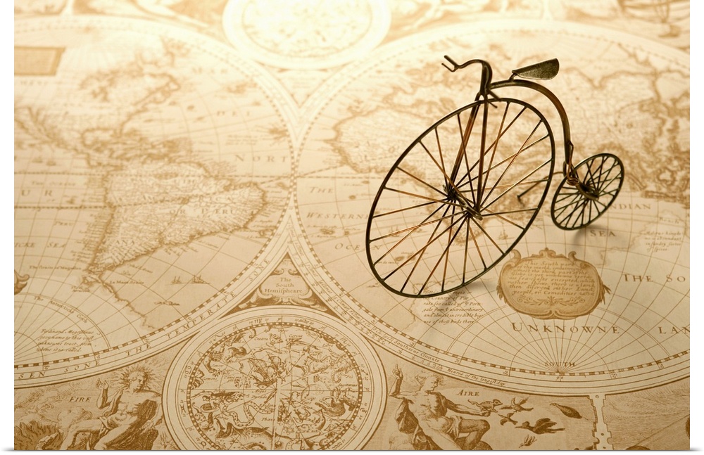 An antique toy bike on top of an old map of the world.