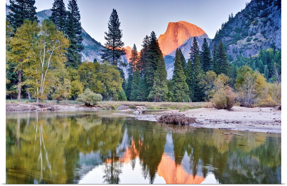 Trees and mountain reflection in river.