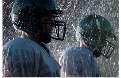 Two American football players in rain, side view