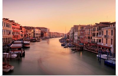 Venetian canal side palaces around Rialto Bridge glow in last of evening light.