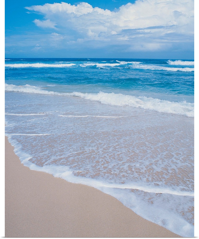 Photograph of small waves lapping on the white sandy beach.