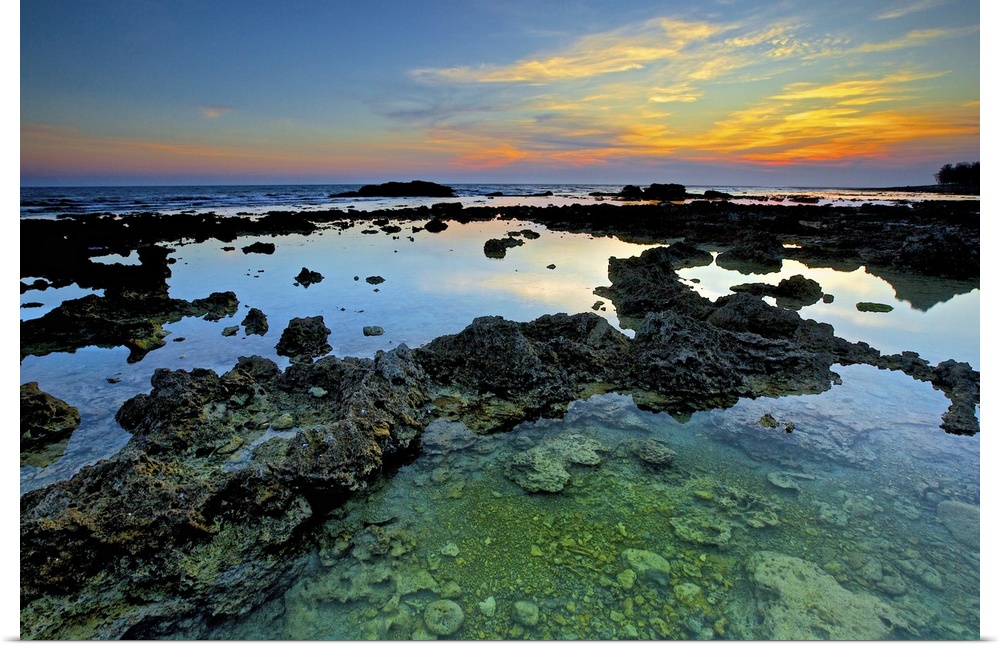 Coral reefs in Wanliton at blue dusk with crystal clear water surrounded and orange clouds above  horizon.