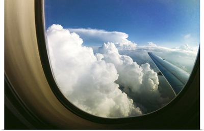Watching the clouds pass by through a window of an airplane