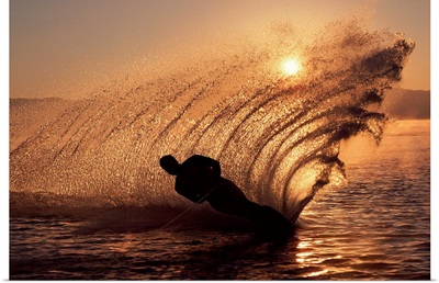 Water-skier at sunset sending up spray of water