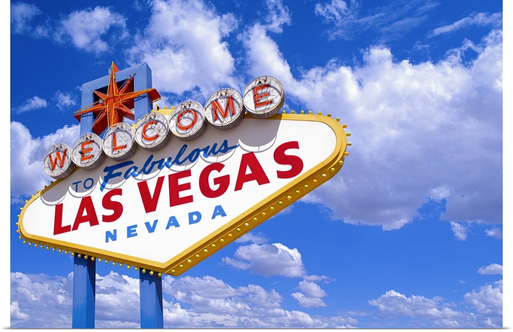 Giant, landscape photograph of the welcome sign in Las Vegas, Nevada, during the day, against a bright blue sky with billo...