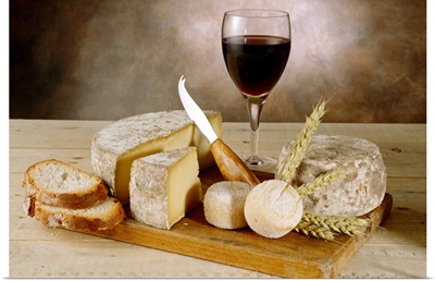 Wine with cheeses and breads on cutting board