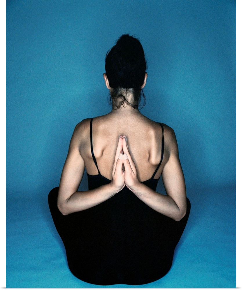Woman sitting in yoga reverse prayer position
