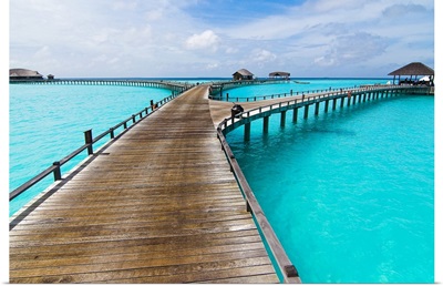 Wooden jetty to seaplane landing over crystal clear water with cloud dusted blue sky.