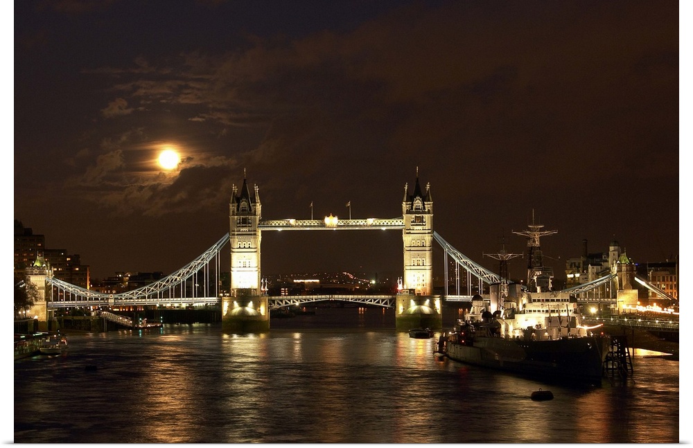The dramatic view looking east along the river Thames past the World War Two warship HMS Belfast towards a full moon risin...