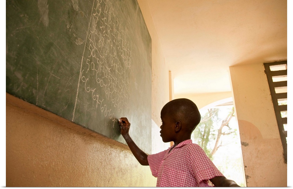 Young male 5-7 in Haiti writing on a blackboard in school
