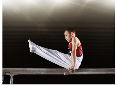 Young male gymnast performing on parallel bars
