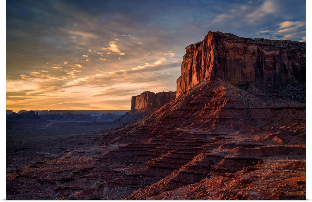 The rising sun spreads warm light across the face of Monument Valley's Mitchell Mesa.