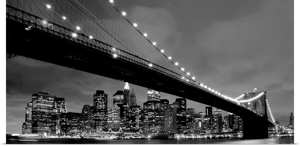 Black and white panoramic of the Brooklyn Bridge with New York City in the background.