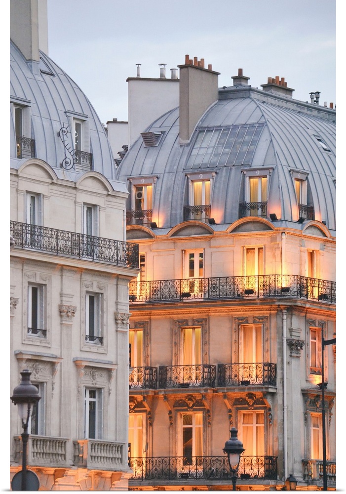 A photograph of Paris apartment buildings at dusk with lights beginning to warm the faade
