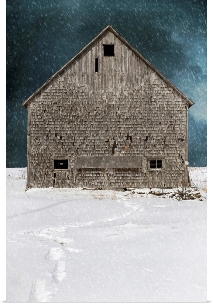 An old abandoned barn in a winter snow storm with footprints.