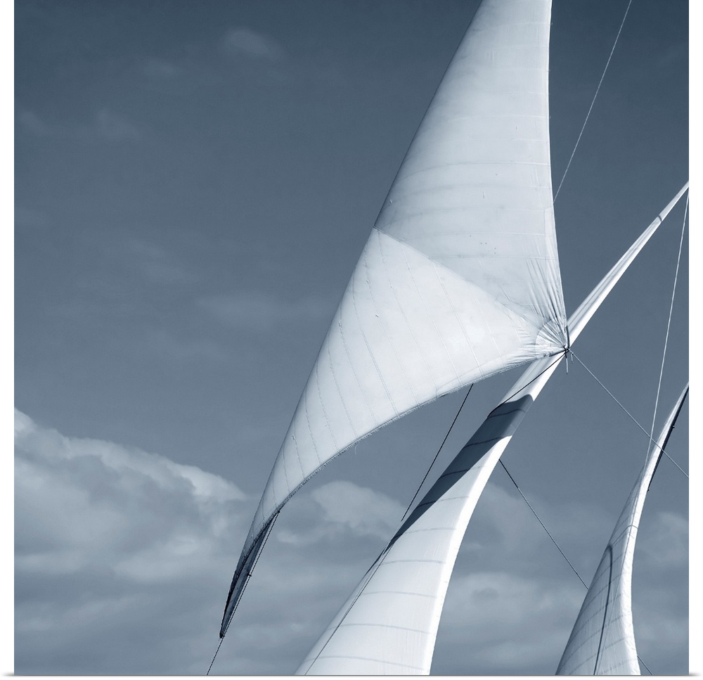 Black and white photograph of three sails against a cloudy sky.