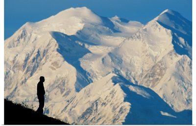 A hiker silhouetted against snow-covered Mount McKinley, Denali National Park, Alaska