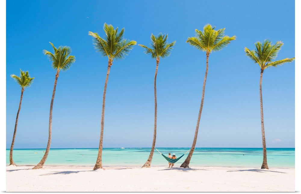 Juanillo Beach (playa Juanillo), Punta Cana, Dominican Republic. Couple relaxing on a hammock on a palm-fringed beach (MR).