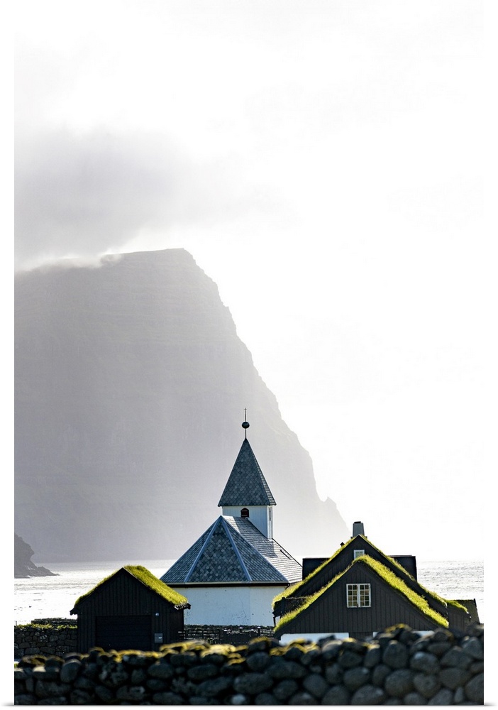 Misty sky over the traditional church of Vidareidi ovelooking a fjord, Vidoy Island, Faroe Islands