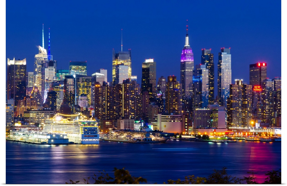 Canvas print of the NYC cityscape lit up in colored lights along a waterfront.