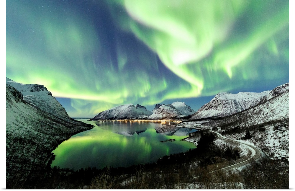 Northern lights and stars light up the snowy peaks reflected in the cold sea Bergsbotn Senja Troms Norway Europe