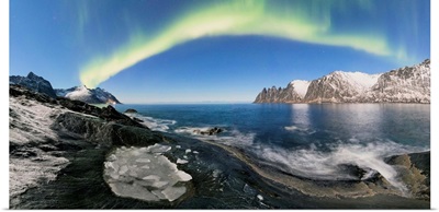 Panorama of frozen sea and rocky peaks illuminated by the Northern Lights, Norway