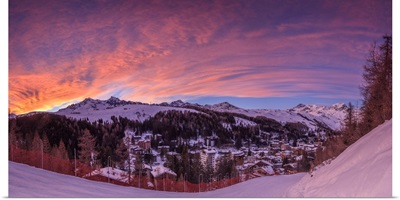 Panorama of the alpine village of Madesimo and snowy ski slopes at sunset