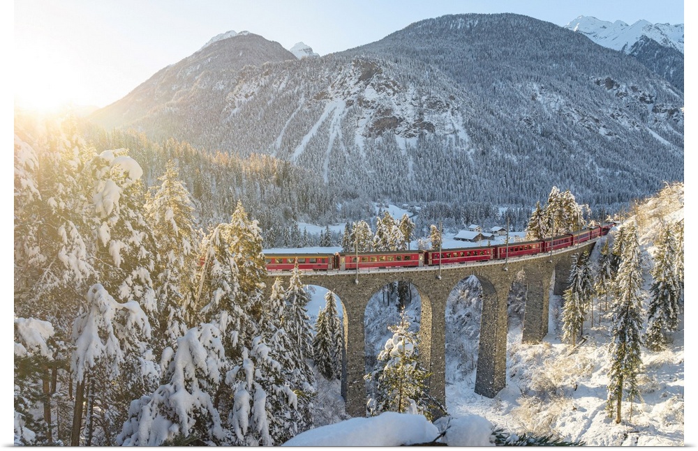 Red train traveling in the winter snowy landscape from Filisur to Tiefencastel railway station, aerial view, Graubunden, S...