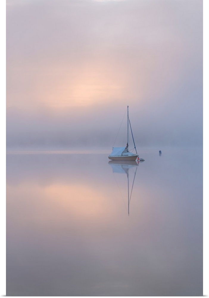 Sailing boat in misty conditions at dawn on a reflective Wimbleball Lake, Exmoor National Park, Somerset, England. Spring ...