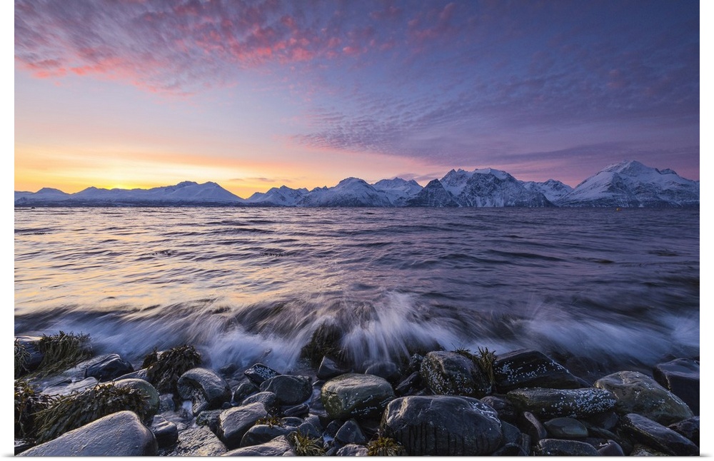 The waves breaking on the stones beach during sunset. Nordmannvik, Kafjord, Lyngen Alps, Troms, Norway, Lapland, Europe.