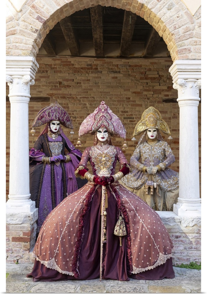 Three women wearing Indian style costumes and masks pose in the cloisters of Chiesa di San Francesco della Vigna, Venice, ...