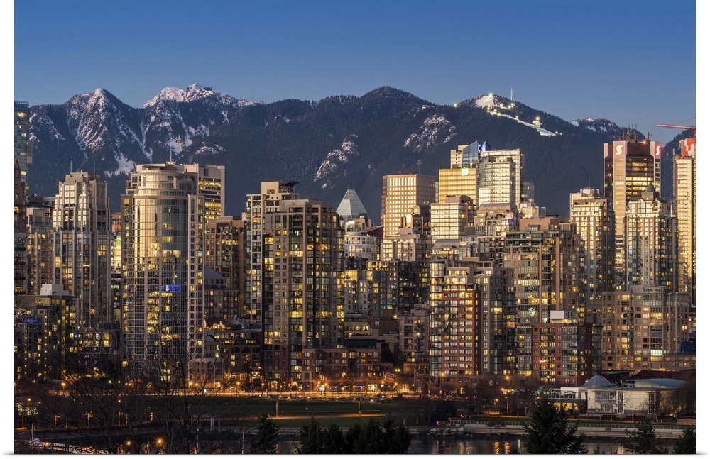 Downtown skyline with snowy mountains behind at dusk, Vancouver, British Columbia, Canada.