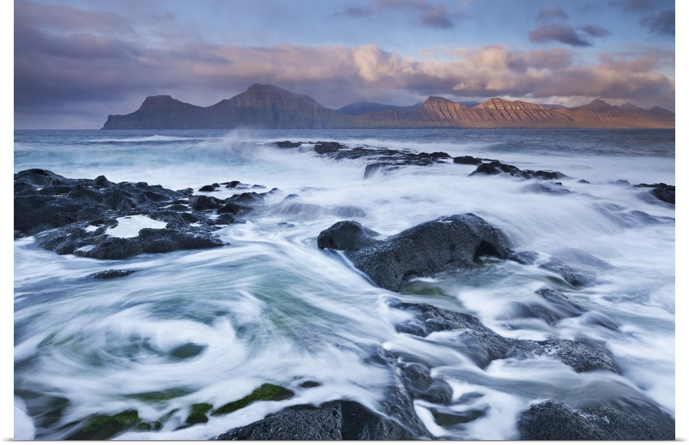 Surging waves break over the rocky shores at Gjogv on the island of Eysturoy, Faroe Islands. Spring