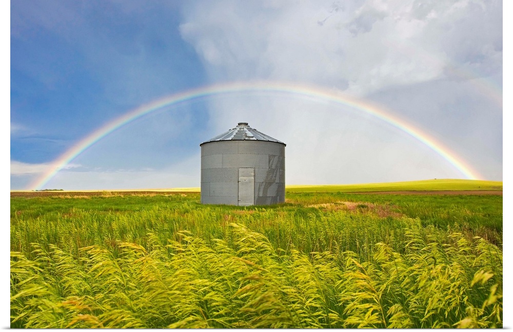 A rainbow over a grain silo and wheat field after a thunderstorm.